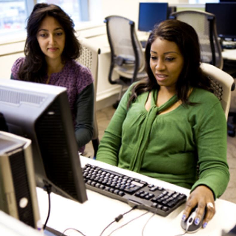 woman on a computer being assisted by another woman