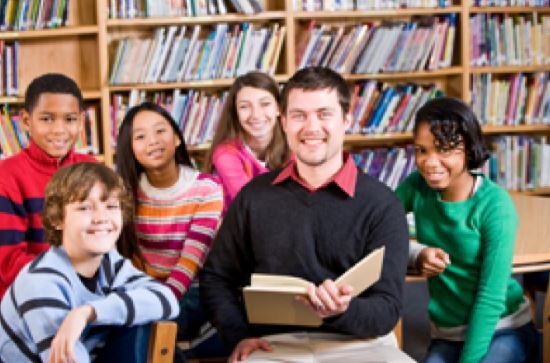 man reading a book to 5 children in a library