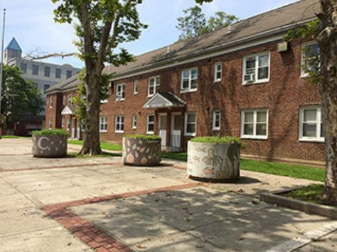 photo of 2 story brick building with trees and sidewalk