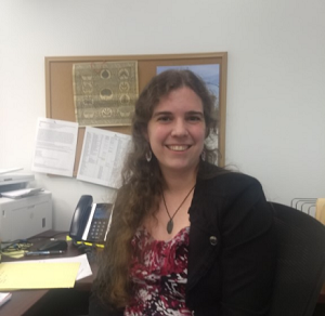 Anna Keegan woman sitting at office desk smiling at camera