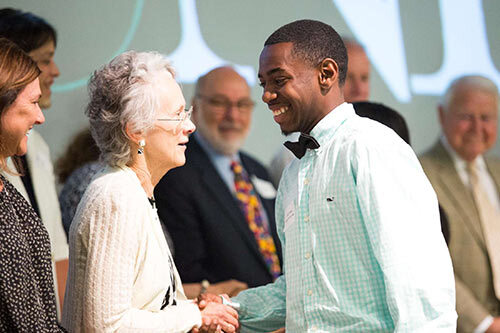 Young man on graduation stage shaking ladies hand