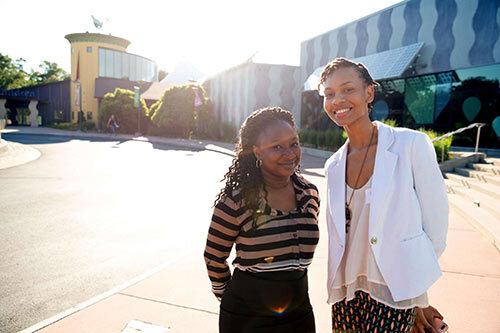 2 young ladies standing outside graduation building smiling