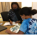 Student getting help from teach both sitting at desk