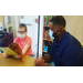 Student reading at table with assistance from teacher