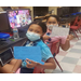 2 girls at computers showing their work wearing covid masks