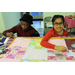 Senior woman with a hat and a girl with glasses working on a quilt on a table