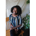 Young lady, Joane Jean Baptiste, sitting on bench inside posing for camera