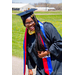 Young lady, Rose Pierre, with glasses on in cap and gown for graduation standing outside smiling at camera