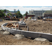 A concrete wall is drying, workers continue work in the background