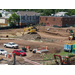 A backhoe on a pile of dirt in the center of the construction site