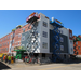 Workers continue to put the white and blue siding on the outside of the building and move on to the next side of the building