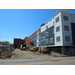 Workers continue to put the white and blue siding on the outside of the building and move on to the next side of the building