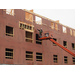 A worker uses a lift to install the sheathing to the outside of the building