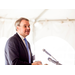 Man with glasses mid speech at podium