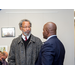 Man in overcoat speaking to man in suit